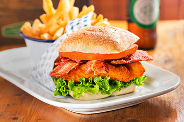 Chicken burger with bacon and lettuce. Fries and beer in restaurant 