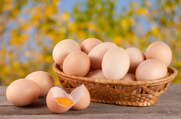 eggs in a wicker basket on a wooden board with blurred garden background