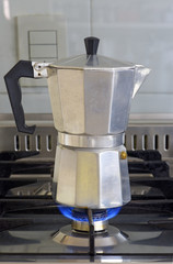 Italian coffee maker on stove with burning fire