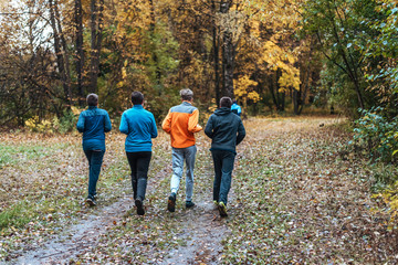Running athletes in the park on a run in the early morning. Several children are running in the woods doing sports. Healthy lifestyle.