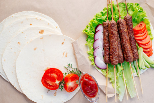 Fast food. Eastern food. Shish kebab, lyulya-kebab, shaverma, pita gyros. Dishes of oriental cuisine lying on pita bread and decorated with greens and vegetables, sauces and French fries. 