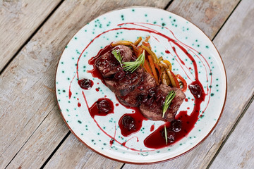 Beef with cherry sauce, top view. Beef tenderloin with sweet sauce on plate. Sliced beef steak in red sauce. Delicious european dish.