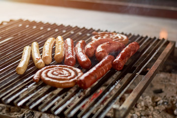 Sausages on grill for barbecue. Sausages and bratwurst grilling on barbecue grill. Appetizing aand delicious meat.