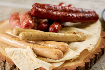 Assorted grilled sausages close up. Assortment of different kinds of grilled sausages on platter close up.
