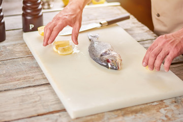 Preparation of a dorado grill. Fresh raw fish and lemon on cutting board. Cooking dorado fish.