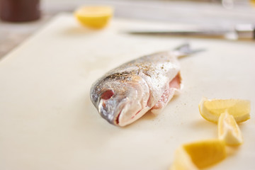 Raw fish with spices and lemon. Fresh fish with lemon on cutting board. Cooking dorado fish.