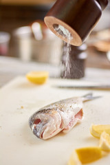 Processing with salt raw fish. Process of cooking dorado fish with spices, salt and lemon. European restaurant kitchen.