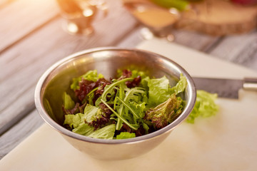 Mixed salad leaves in stainless bowl. Fresh mix of green and purple salad on table. Dish cooking at restaurant.