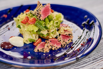 Nisuaz salad with lettuce and tuna. Delicious food on plate. Tasty dinner on table of restaurant.