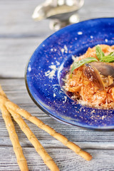 Tasty pasta on plate and bread sticks. Appetizing pasta with red sauce and seafood, bread sticks on table. Restaurant of italian food.