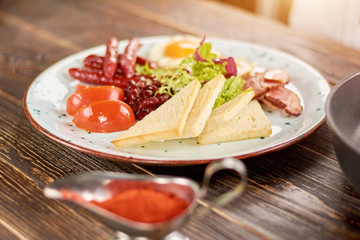 English breakfast on plate. English breakfast with toasts, tomatoes, beans, fried eggs, baked sausages and bakon. English breakfast in restaurant.
