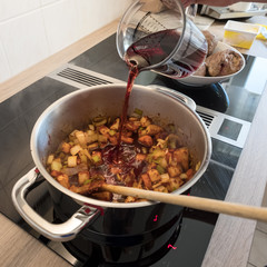 Gemüse im Topf beim braten mit Rotwein ablöschen