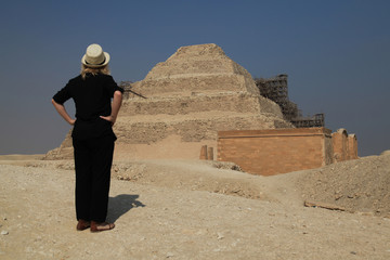 Frau von hinten fotografiert betrachtet eine Stufenpyramide in Ägypten