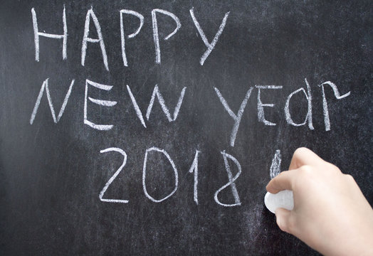 Happy New Year 2018 Hand Written With White Chalk On The Blackboard. Children Hand Finish To Write Year 2018. Concept Of New Year Holiday At School  