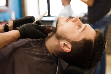 Obraz na płótnie Canvas Man getting haircut by hairstylist at barbershop