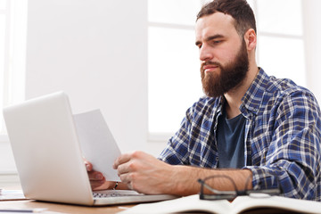 Young concentrated businessman read documents in modern white office