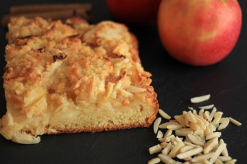 Fresh Homemade Apple Pie with almond slivers, apple and cinnamon sticks on black background