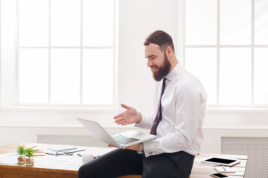 Happy businessman with laptop in modern white office
