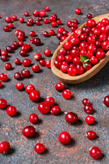 Juicy ripe berry cranberries in a wooden spoon on a dark background with copy space