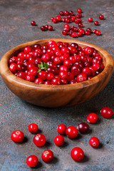 Juicy ripe berry cranberries in a wooden bowl on a dark background with copy space