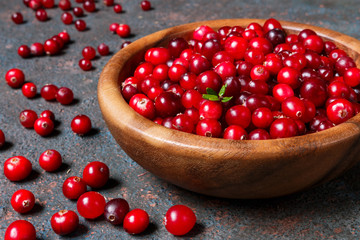 Juicy ripe berry cranberries in a wooden bowl on a dark background with copy space