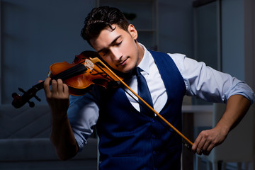 Young musician man practicing playing violin at home