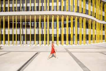 Woman in red dress on the modern yellow building wall background. Abstract geometric composition