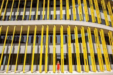 Woman in red dress on the modern yellow building wall background. Abstract geometric composition