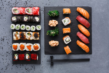 Top view set of sushi maki and rolls on rustic grey and sesame background