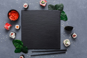 Square black slate plate with sushi on rustic grey backround copy space