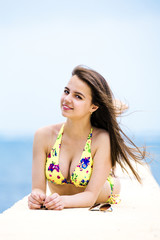 Relaxing young woman on pier at the sea in summer day. Skinny girl in swimsuits posing near sea.
