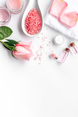 Spa products with rose oil. Cream, lotion and salt on white background top view copyspace