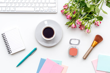 female work space with flowers, coffee, cosmetics and notebook white background top view mockup
