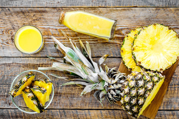 Freshly squeezed pineapple juice near fruit slices on wooden background top view