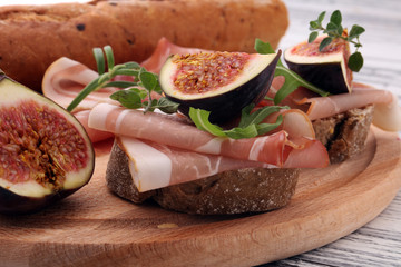Sandwich with figs and prosciutto. Antipasti gourmet bruschetta snack.