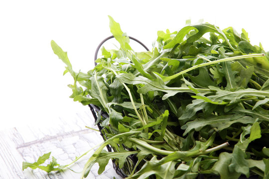 Fresh green arugula in basket on wooden table. Arugula is rich in vitamins and trace elements.