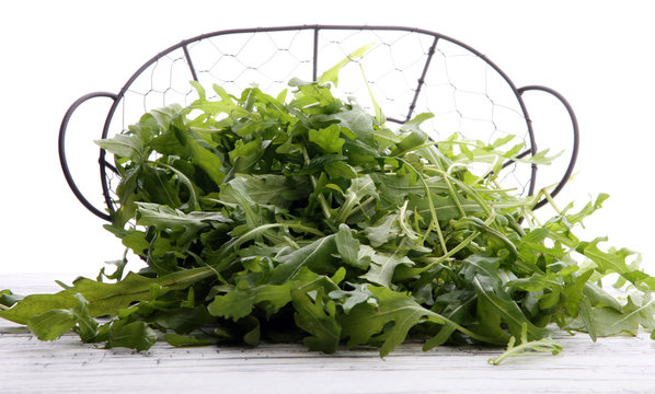 Fresh green arugula in basket on wooden table. Arugula is rich in vitamins and trace elements.