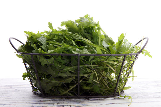Fresh green arugula in basket on wooden table. Arugula is rich in vitamins and trace elements.