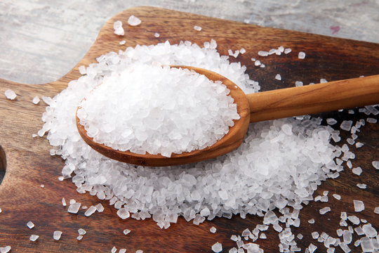 Fototapeta sea salt with wooden spoon and crystals of salt on wooden background.