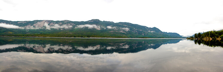 Fototapeta na wymiar View of a fjord in calm misty morning with low clouds