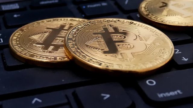 Gold Bitcoin BTC coins rotating on laptop keyboard. Digital coin btc money crypto currency on bitcoin farm in digital cyberspace. Worldwide virtual internet cryptocurrency and digital payment system