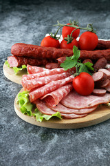 Food tray with delicious salami, pieces of sliced ham, sausage, tomatoes, salad and vegetable - Meat platter with selection - Cutting sausage and cured meat