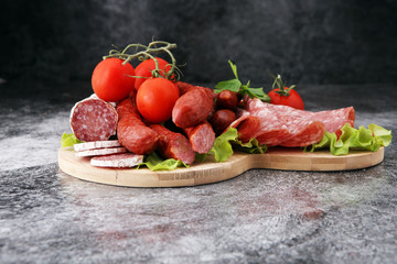 Food tray with delicious salami, pieces of sliced ham, sausage, tomatoes, salad and vegetable - Meat platter with selection - Cutting sausage and cured meat