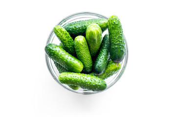 Fresh cucumbers in bowl on white background top view copyspace