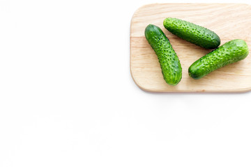 Make salad with fresh cucumbers. Vegetables on cutting board on white background top view copyspace