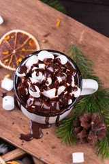 Hot chocolate with marshmallows, cinnamon and spices on a wooden board.