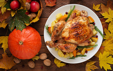 Roasted turkey garnished with cranberries on a rustic style table decorated with pumpkins, orange, apples and autumn leaf. Thanksgiving Day. Flat lay. Top view