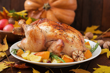 Roasted turkey garnished with cranberries on a rustic style table decorated with pumpkins, orange, apples and autumn leaf. Thanksgiving Day.
