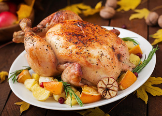 Roasted turkey garnished with cranberries on a rustic style table decorated with pumpkins, orange, apples and autumn leaf. Thanksgiving Day.