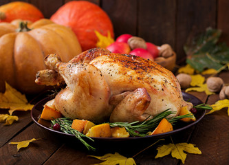 Roasted turkey garnished with cranberries on a rustic style table decorated with pumpkins, orange, apples and autumn leaf. Thanksgiving Day.